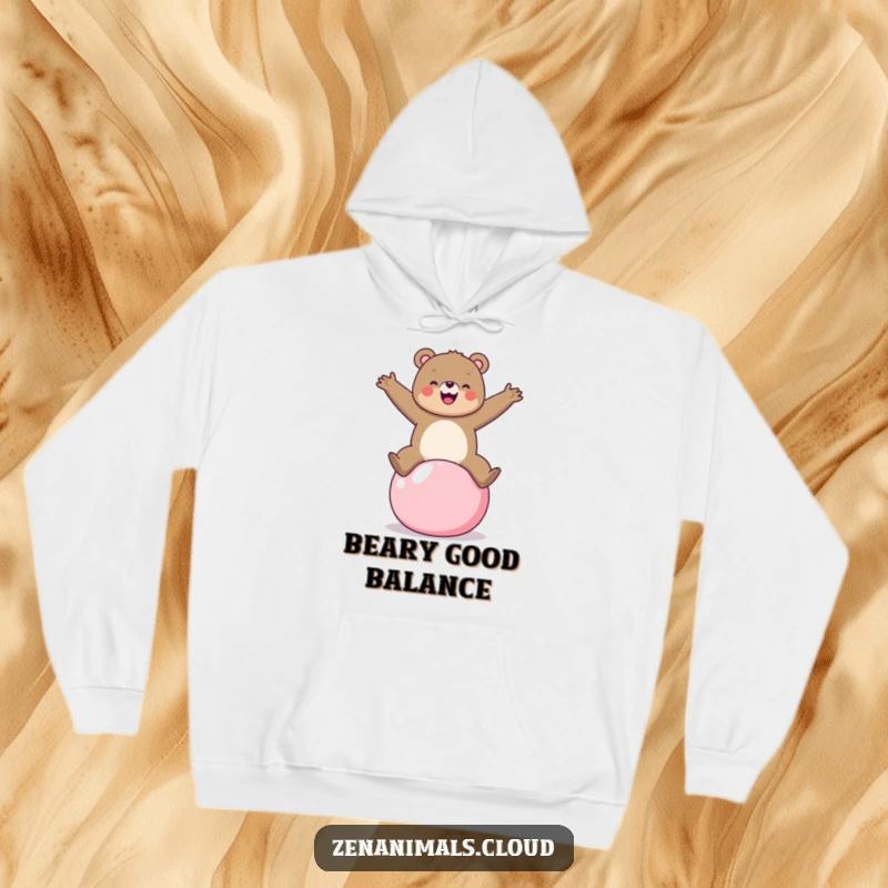 Funny cheerful bear on a yoga ball hoodie, arms outstretched, ideal for cozy fitness enthusiasts.
